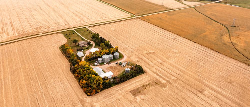 一个农场的航拍照片，有田地、粮仓、房屋、机械棚和设备